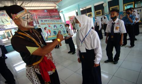 Seorang guru mengenakan kostum wayang saat melakukan sosialisasi protokol kesehatan pada kegiatan Masa Orientasi Sekolah (MOS) di SMPN 9 Tegal, Jawa Tengah, Selasa (7/9/2021). Kegiatan jelang pembelajaran tatap muka tersebut untuk meningkatkan disiplin pelajar pentingnya penggunaan masker dan menerapkan protokol kesehatan ketika dilingkungan sekolah dan ditempat umum untuk menekan penyebaran COVID-19