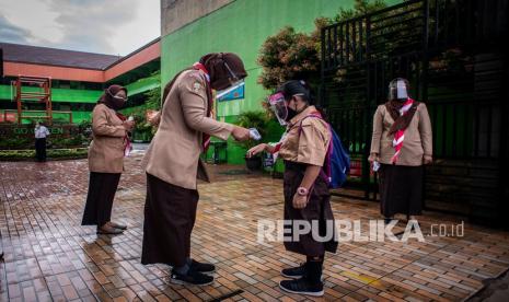 Seorang Guru mengukur suhu tubuh murid pada hari pertama uji coba pembelajaran tatap muka di SD Negeri Kenari 08 Pagi, Jakarta, Rabu (7/4/2021). Pemprov DKI Jakarta melakukan uji coba pembelajaran tatap muka terbatas di 85 sekolah dari jenjang SD hingga SMA mulai 7 April hingga 29 April 2021 dengan kapasitas dalam ruangan maksimum 50 persen dan penerapan protokol kesehatan yang ketat. 