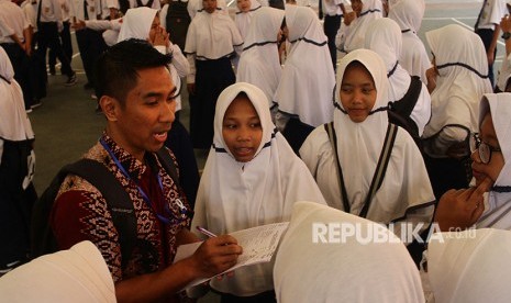 Seorang guru mengumpulkan siswa peserta Ujian Nasional Berbasis Kompetensi (UNBK) - SMP saat terjadi gangguan server di lapangan di SMP 12, Malang, Jawa Timur, Senin (23/4). 