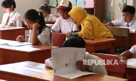 Seorang guru pedamping membacakan soal Ujian Sekolah Berstandar Nasional (USBN) kepada murid berkebutuhan khusus di SD Inklusi. Ilustrasi (Foto diambil sebelum masa pandemi)