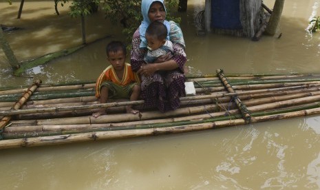 Seorang ibu bersama anaknya berada di atas rakit saat melintasi banjir di Baureno, Bojonegoro, Jawa Timur, Jumat (2/12).