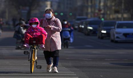 Seorang ibu dan anaknya melintasi jalanan di Beijing.  China akan memprioritaskan upaya stabilisasi lapangan kerja dan harga untuk membangkitkan ekonomi.