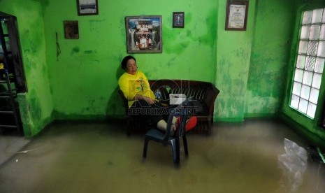    Seorang ibu duduk di dalam rumahnya yang terendam banjir di kawasan pemukiman Kampung Melayu Besar, Jakarta, Rabu (29/1).   (Republika/Prayogi)