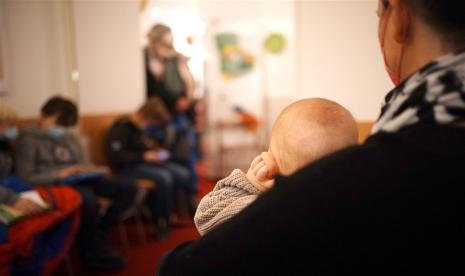 Seorang ibu memangku anaknya di ruang tunggu dokter anak di Berlin, Jerman, 6 Desember 2022. Kasus penyakit pernapasan akibat respiratory syncytial virus (RSV) di Jerman meningkat berbarengan dengan Covid-19 dan influenza hingga terjadi kekurangan tempat tidur di rumah sakit untuk merawat anak-anak yang menderita penyakit pernapasan dengan gejala parah. 