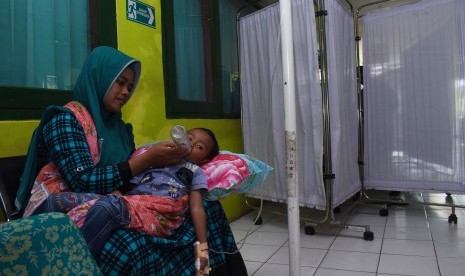 Seorang ibu memangku anaknya yang diduga terserang Demam Berdarah (DB) di lorong Rumah Sakit Umum Daerah (RSUD) Dolopo, Kabupaten Madiun, Jawa Timur, Senin (4/2/2019). 