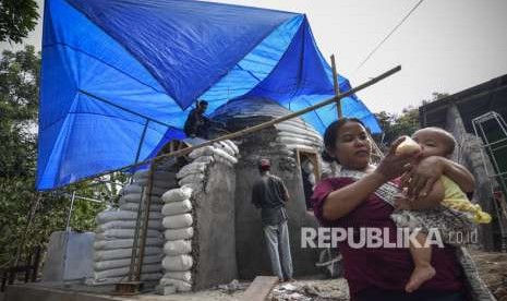 Seorang ibu memberi susu bayinya dekat bangunan rumah Hunian Tetap (Huntap) miliknya di Dusun Montong Dao, Desa Teratak, Kecamatan Batukliang Utara, Lombok Tengah, NTB, Jumat (5/10).