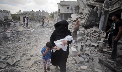 Seorang ibu mengajak anaknya berjalan melewati reruntuhan bangunan di Jalur Gaza.