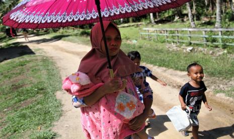 Seorang ibu menggendong anak balitanya menuju rumah Pos Pelayanan Terpadu (Posyandu) Ilustrasi.