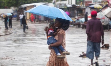 Seorang ibu menggendong anaknya di tengah hujan akibat Topan Matthew di Port-au-Prince, Haiti.