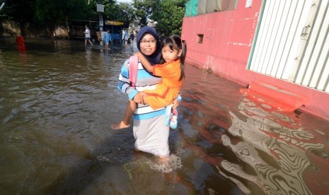 Seorang ibu menggendong anaknya yang akan berangkat ke sekolah menembus banjir di Perumahan Ciledug Indah 1, Tangerang, Banten.