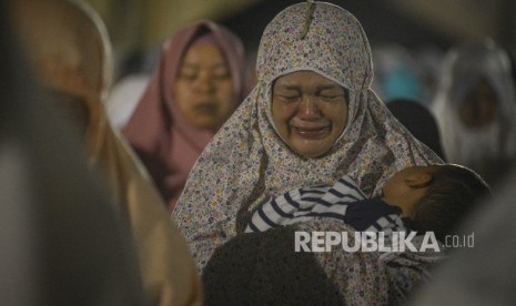 Seorang ibu yang menggendong anaknya menangis saat melakukan Shalat Subuh Berjamaah di Masjid Pusat Dakwah Islam (Pusdai) Kota Bandung, Jawa Barat, Senin (12/12). 