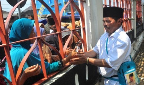 Seorang jamaah calon haji menyalami keluarga dari balik pagar Embarkasi Haji Adisumarmo, Donohudan, Boyolali, Jawa Tengah, Minggu (23/8).