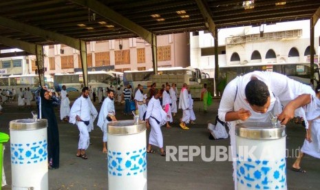 Seorang jamaah haji minum air putih saat berjalan kaki menuju Arafah, melintasi kawasan Mahbas Jin di Makkah. (Republika/ Amin Madani) 