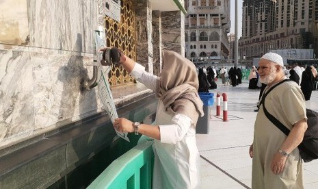 Seorang jamaah mengambil plastik //roll// yang disediakan di pintu masuk Masjid Al Haram. Plastik tersebut biasanya dimanfaatkan jamaah untuk menyimpan sandal saat masuk ke Masjid Al Haram.