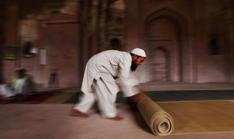 Seorang jamaah menggulung tikar sajadah seusai shalat Jumat pertama Ramadhan di masjid peninggalan era Mughal di New Delhi, India, Jumat 12 Juli 2013.