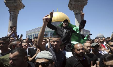 Seorang jamaah Muslim mengenakan bendera Hamas saat melakukan protes terhadap serangan udara Israel di Jalur Gaza, Palestina setelah salat Jumat di Masjid Kubah Batu di kompleks Masjid Al-Aqsa di Kota Tua Yerusalem, Jumat, 14 Mei 2021.