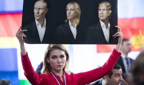 Seorang jurnalis memegang poster bergambar presiden Rusia, Vladimir Putin (kiri), Presiden Front Nasional sayap kanan Prancis, Marine Le Pen (tengah), dan Presiden terpilih AS, Donald Trump (kanan)