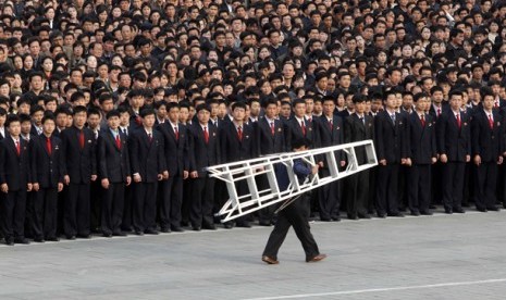  Seorang juru kamera Korea Utara tengah melintas di tempat berkumpulnya warta di lapangan Kim Il Sung di Pyongyang, Korea Utara. Unjuk rasa ini mengecam pernyataan Presiden Korea Selatan Lee Myung-bak yang mengatakan pesta peringatan 100 tahun kelahiran Ki