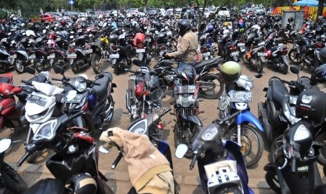   Seorang juru parkir mengarahkan pengendara saat parkir di kawasan IRTI MOnas, Jakarta Pusat, Selasa (26/5).