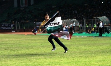 Seorang Juventini masuk ke lapangan sambil membentangkan bendera Palestina saat laga Juventus VS ISL Star di Stadion GBK, Jakarta, Rabu (6/8).