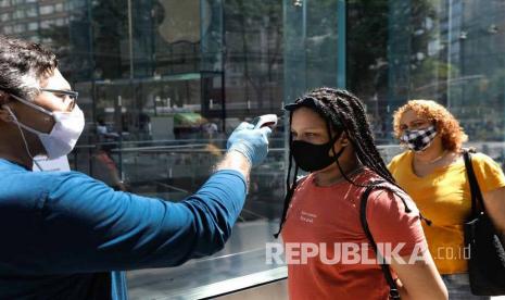 Seorang karyawan Apple (kiri) mengukur suhu pelanggan sebelum masuk ke toko Apple di Broadway di New York, New York, AS, Jumat (19/6). Pada pembukaan fase dua setelah selama 100 hari masa lockdown, Kota New York kembali membuka aktivitas ekonomi diantaranya membolehkan makan di luar ruangan di restoran, salon, pembukaan kantor, perusahaan real estat, inspeksi dan pertunjukan langsung, penjualan kendaraan, sewa ritel, layanan perbaikan dan layanan kebersihan dengan tetap menerapkan protokol kesehatan.  