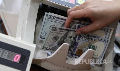 Ilustrasi seorang karyawan melayani penukaran uang dolar AS di sebuah gerai Kegiatan Usaha Penukaran Valuta Asing Bukan Bank (KUPVA BB). 