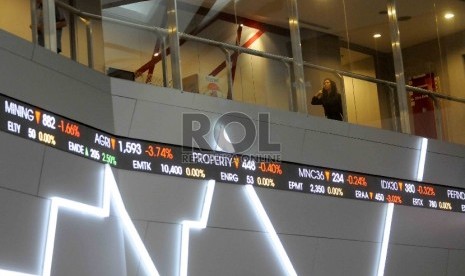 Seorang karyawan melintas didekat layar elektronik pergerakan Indeks harga saham gabungan (IHSG) di gedung Bursa Efek Indonesia, Jakarta.