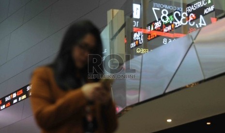 Seorang karyawan melintas didekat layar elektronik pergerakan Indeks harga saham gabungan (IHSG) di gedung Bursa Efek Indonesia, Jakarta, Jumat (11/9).