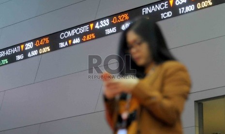 Seorang karyawan melintas didekat layar elektronik pergerakan Indeks harga saham gabungan (IHSG) di gedung Bursa Efek Indonesia, Jakarta, Jumat (11/9).