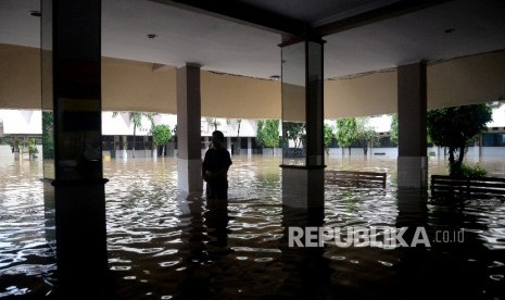  Seorang karyawan melintasi banjir yang menggenagi halaman sekolah SMA Negeri 8 , Bukit Duri, Jakarta, Kamis (16/2).