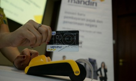 Seorang karyawan mencoba mini ATM Bank Mandiri untuk melakukan pembayaran pajak di Plaza Mandiri Jakarta, Selasa (15/12).