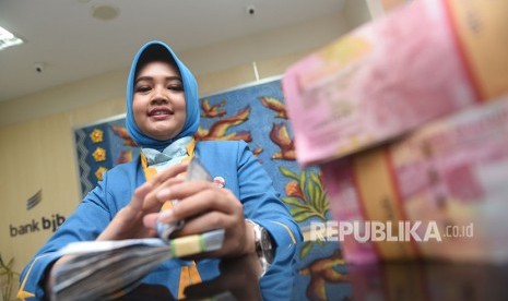 Seorang karyawan menghitung uang nasabah di bank bjb.