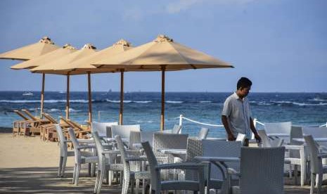 Seorang karyawan merapikan deretan kursi dan meja restoran yang terdapat di pinggiran Pantai Senggigi, Kecamatan Batulayar, Lombok Barat, NTB, Kamis (6/9).