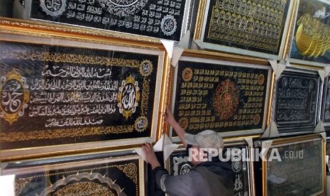 Seorang karyawan toko frame merapihkan display kaligrafi di tokonya di Jakarta, Senin (21/3). 