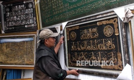 Seorang karyawan toko frame merapihkan display kaligrafi di tokonya di Jakarta, Senin (21/3). 