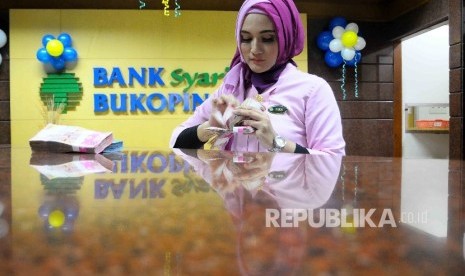 Seorang karyawati tenhgah menghitung uang di Banking Hall Bank Syariah Bukopin, Jakarta, Kamis (15/12). 