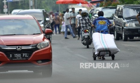  Seorang kuli angkut membawa barang bawaannya melintas di Pasar Tanah Abang, Jakarta Pusat, Senin (10/7).