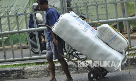 Seorang kuli angkut membawa barang bawaannya.