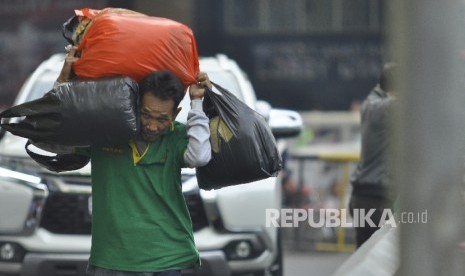 Seorang kuli panggul membawa barang bawaannya melintas di Pasar Tanah Abang, Jakarta Pusat, Senin (10/7).