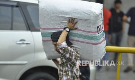 Seorang kuli panggul membawa barang bawaannya melintas di Pasar Tanah Abang, Jakarta Pusat, Senin (10/7). 