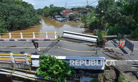 Seorang laki-laki melintas di jembatan yang rusak akibat diterjang banjir di Desa Meninting, Kecamatan Batulayar, Lombok Barat, NTB, Selasa (7/12/2021). Hujan deras dan luapan air sungai Meninting yang terjadi pada Senin (6/12) menyebabkan rusaknya jembatan Meninting yang menghubungkan antara Kota Mataram dan Kabupaten Lombok Barat.