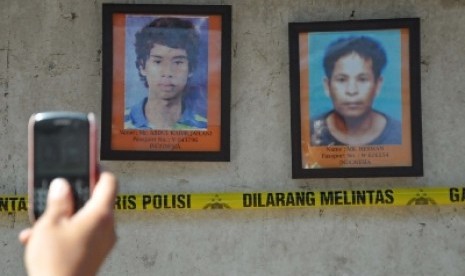 Seorang laki-laki mengambil gambar 2 foto TKI meninggal yang dipajang di lokasi otopsi di pemakaman keluarga Dusun Pancor Kopong, Desa Pringgesela, Kecamatan Pringgesela, Selong, Lombok Timur, NTB, Kamis (26/4). 