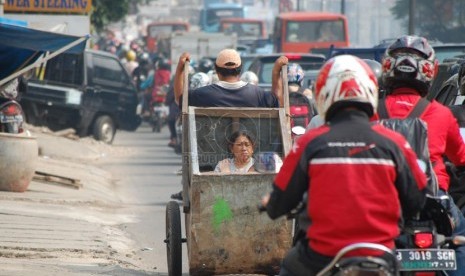 Seorang lelaki dari keluarga miskin mengangkut anak dan istrinya dengan gerobak di Jalan Panglima Polim, Jakarta Selatan, Selasa (15/4). (foto: Raisan Al Farisi)