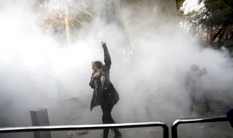 Seorang mahasiswa berdemonstrasi di depan Universitas Teheran, Teheran, Iran, Sabtu (30/12).