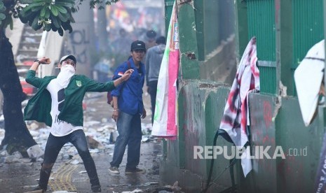 Seorang mahasiswa melemparkan batu ke arah polisi saat kericuhan dalam unjuk rasa di depan kompleks Parlemen di Jakarta, Selasa (24/9/2019). 