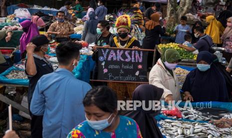 Seorang mahasiswa Universitas Riau mengenakan pakaian adat Papua sambil melakukan sosialisasi vaksinasi COVID-19 dan protokol kesehatan di pasar rakyat Kelurahan Tangkerang Labuhai, Kota Pekanbaru, Provinsi Riau, Kamis (1/4/2021). Mahasiswa UNRI menggunakan dana swadaya untuk melakukan sosialisasi tersebut sebagai bentuk pengabdian ke masyarakat dalam program Kuliah Kerja Nyata (Kunkerta) UNRI. 