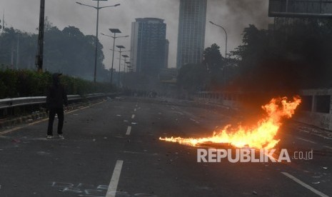 Seorang mahasiwa melintas di jalan Tol saat terjadi bentrokan dengan petugas kepolisian saat berunjuk rasa di depan gedung DPR RI, Jakarta, Selasa (24/09/2019).