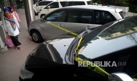 Seorang melintas disamping mobil sitaan milik bos First Travel di halaman Bareskrim Polri, Jakarta, Senin (14/8).