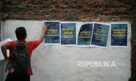  Seorang memempelkan poster acara kegiatan peduli sosial bertajuk Cahaya Tanah Gusuran di Lokasi Gusuran Bukit Duri, Jakarta, Sabtu (15/10).