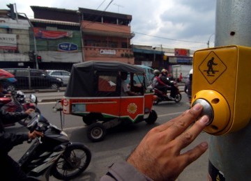 Seorang menggunakan tombol penyeberangan dilampu merah kawasan Pasar Jatinegara, Jakarta Timur, Senin (6/2). (Republika/Prayogi)